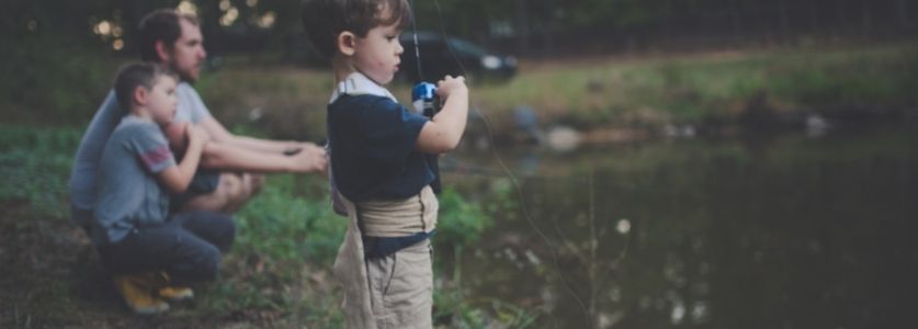 toddler fishing with his dad at the lake