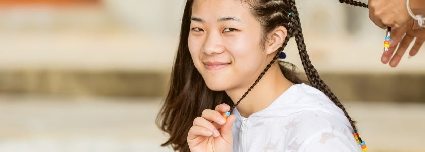 asian girl smiling while having her hair braided