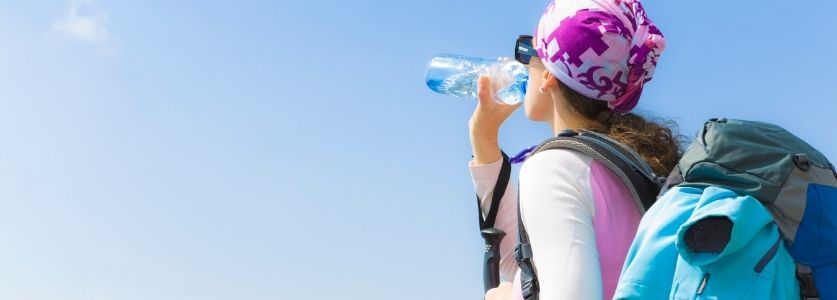 hiker drinking water under hot sun
