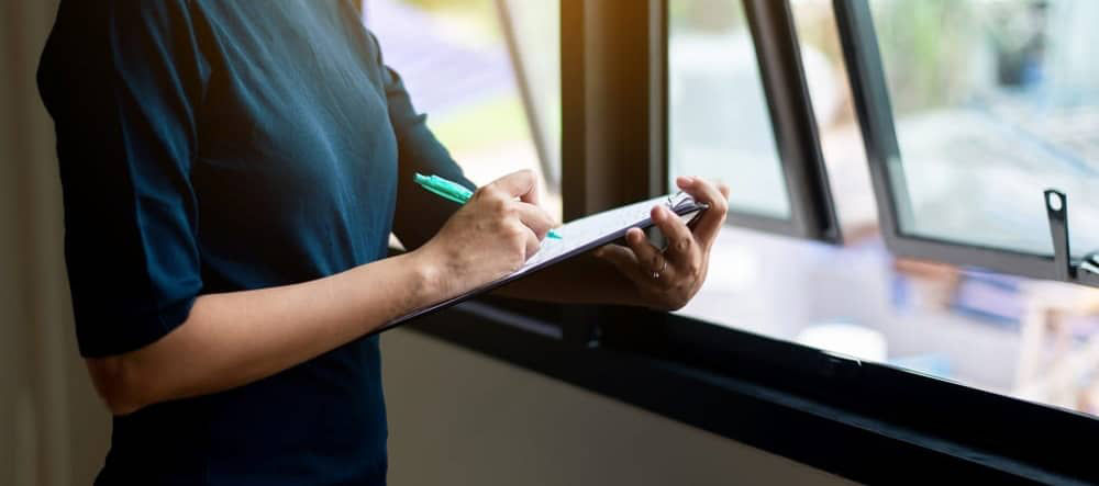 Women home inspection surveyor and writing note on clipboard at a new property