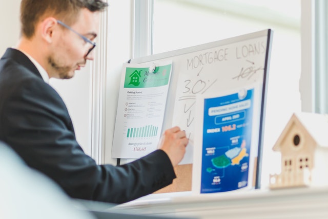 a man writing on a board about loans and mortgages