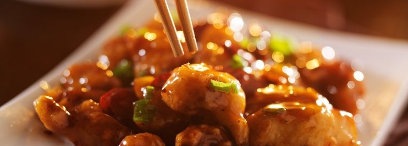 chopsticks grabbing a piece of orange glaze chicken