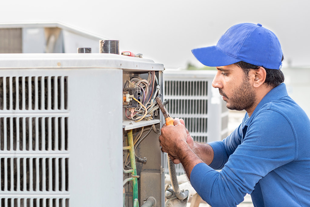 man repairing outdoor air conditioning unit