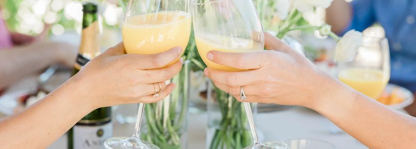 two brunch revelers clanking champagne