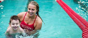 swim school swimming teacher with smiling toddler in pool