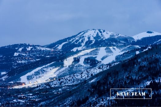 A snowy bald mountain in the background with Park CIty in the foreground