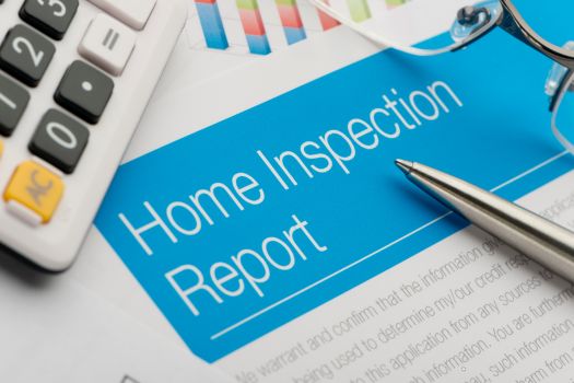 Home Inspection Report on a desk with a pen and calculator