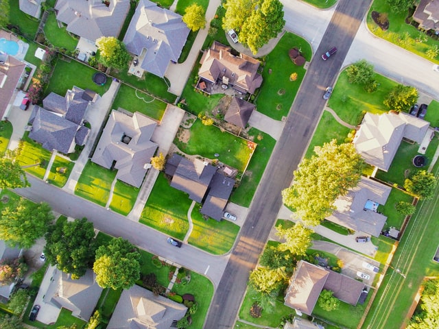 A bird's eye view of an Edmonton neighborhood with houses and large green backyards