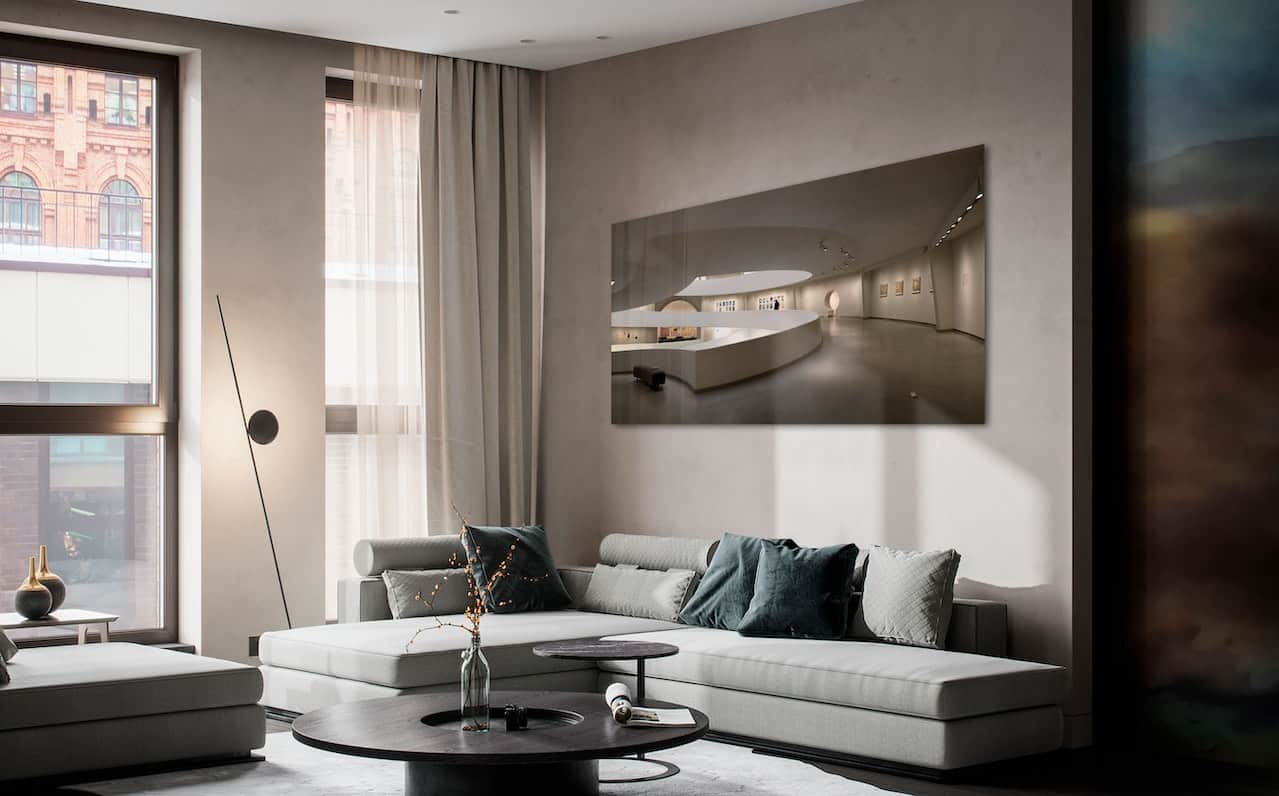 A modern interior living room of an apartment with a grey couch and light grey walls.