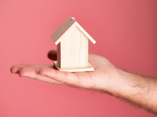 a hand holding a small wooden house