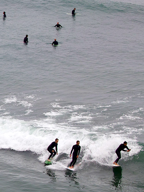 trio of surfers catching a wave on encinitas beach