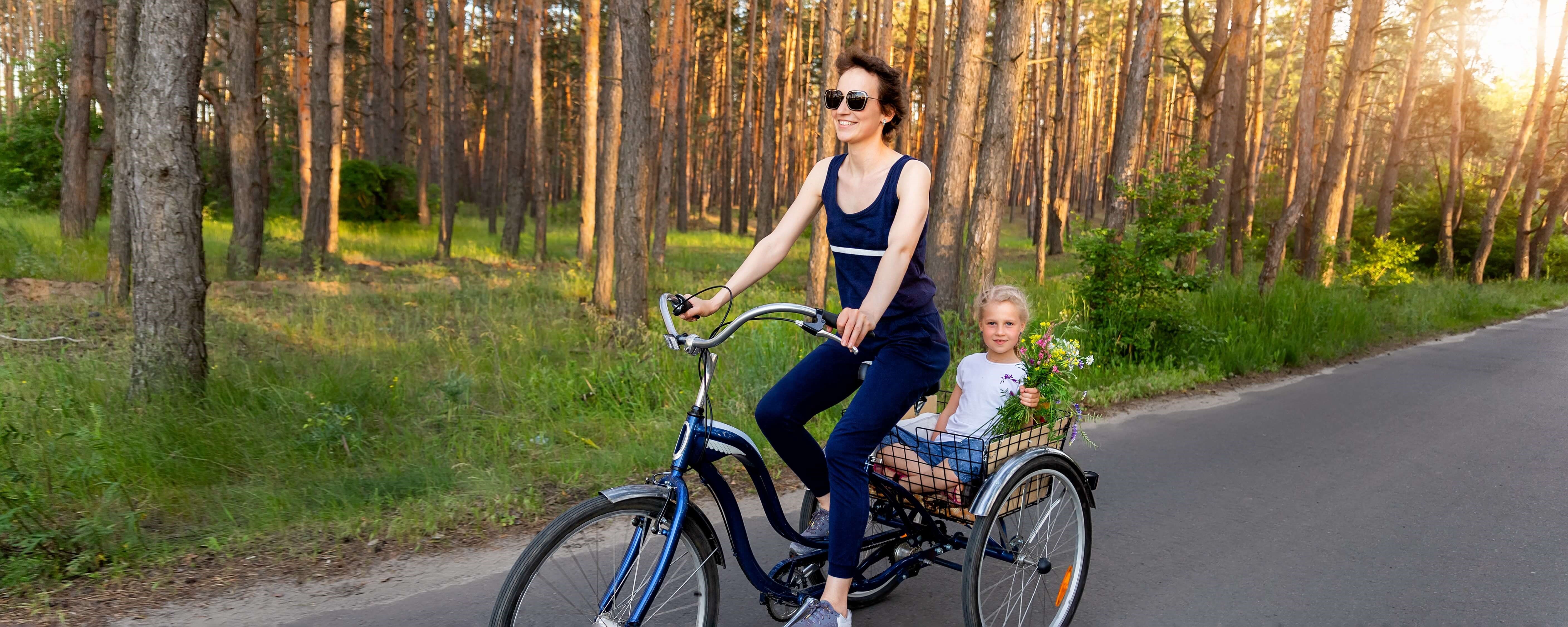 woman riding bike with child in wooded area