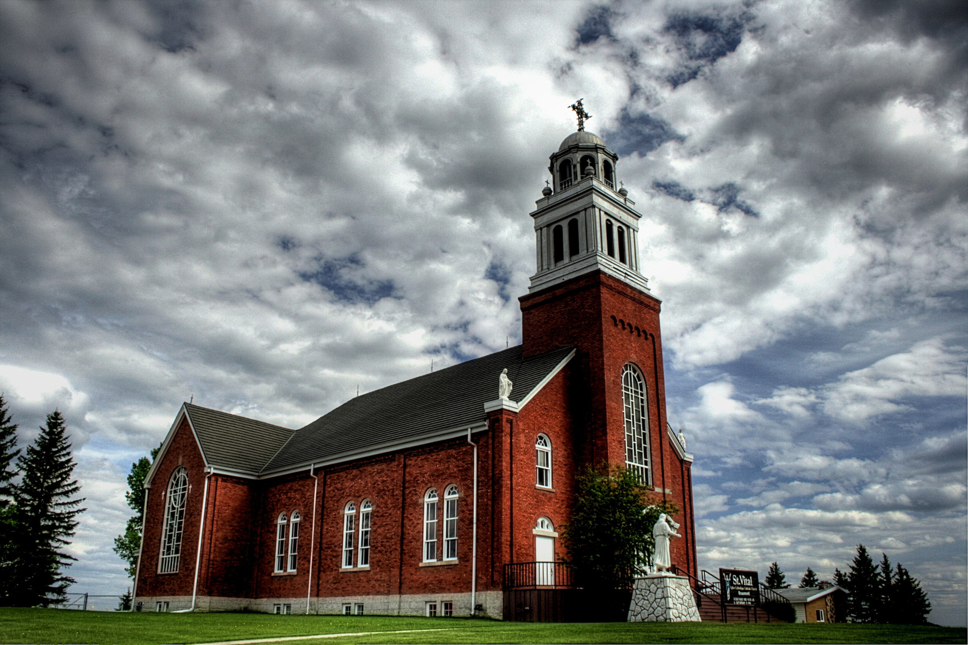 Long shot of Saint Vital Roman catholic church, in Beaumont, against the sky filled with clouds.