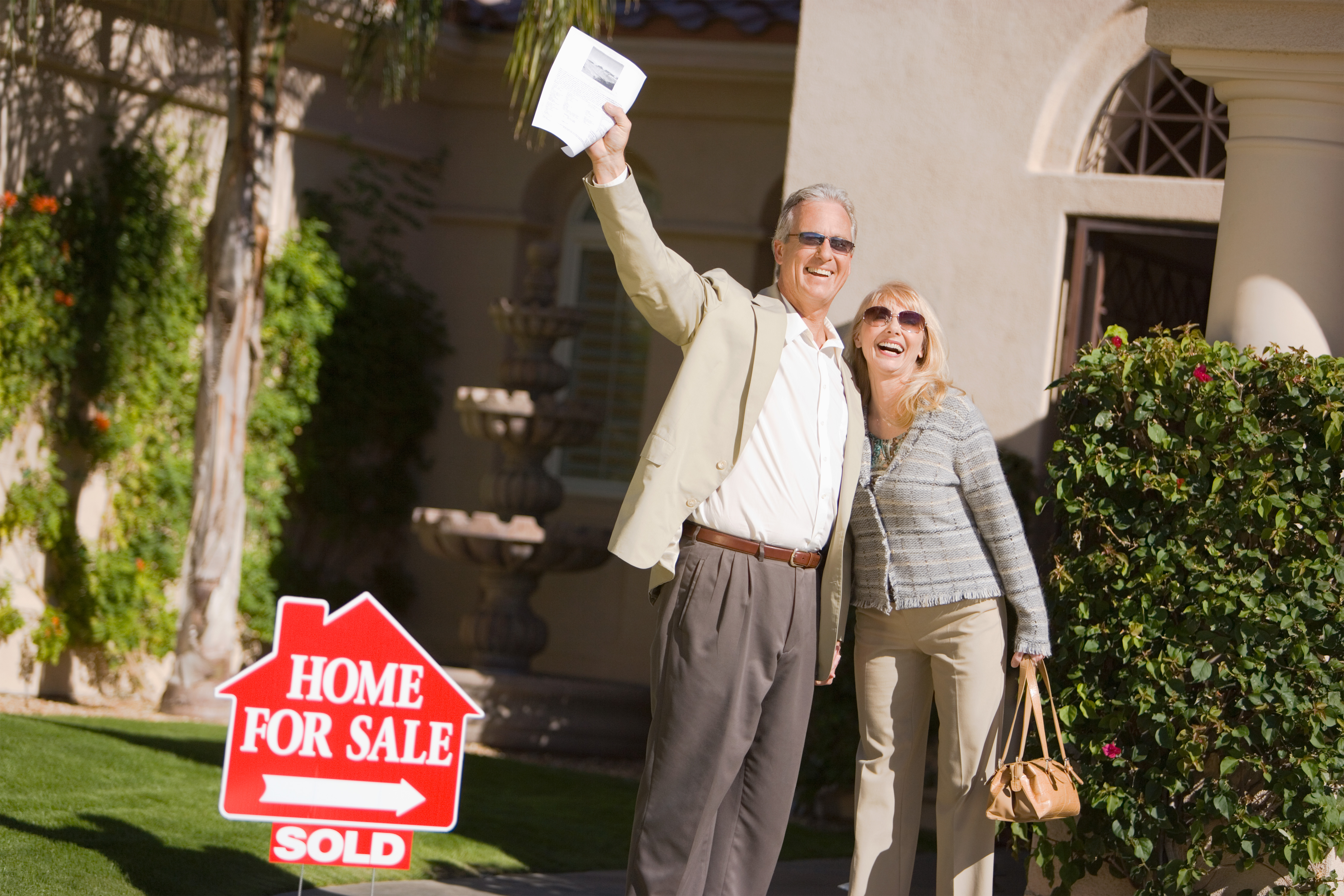 couple with sign showing sold house