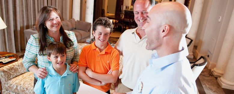 Experienced male REALTOR® showing a home for sale to a family.