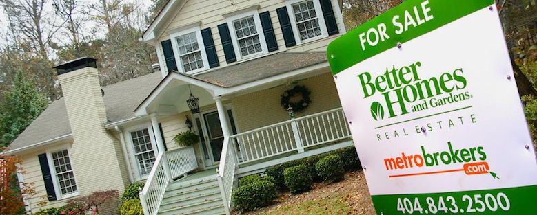 Two story home with front porch for sale with BHGRE Metro Brokers yard sign.