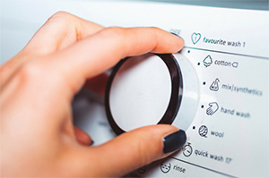 Hand on washing machine knob - Coldwell Banker Paradise
